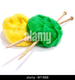 Large ball of red and green mohair wool or yarn pierced with large wooden knitting needles against white background. Stock Photo