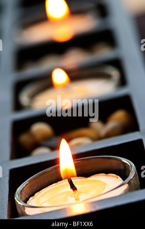 Burning candles in glass holders and wooden stand Stock Photo