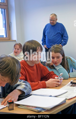 kids at school, one using his mobile phone during class Stock Photo