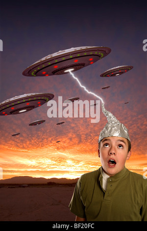 A boy wearing a tin-foil hat observes a squadron of UFOs & is struck by lightning from one. Stock Photo