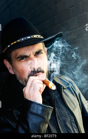 Man with beard in cowboy hat smoking cigar Stock Photo