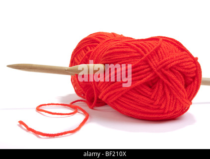 Large ball of red  wool or yarn pierced with large wooden knitting needles against white background. Stock Photo