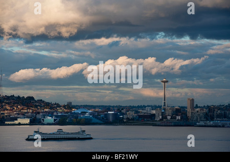 A dramatically lit view of the Seattle Space Needle and a ferry boat crossing Elliott Bay to Bainbridge Island. Washington State Stock Photo