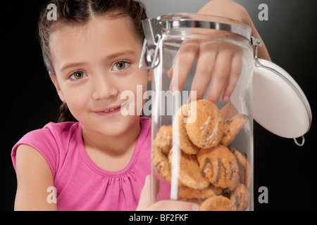 Girl putting her hand into a cookie jar Stock Photo