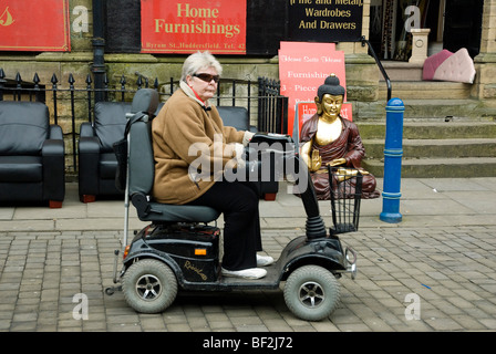 Pensioner on mobility scooter and buddha statue Stock Photo