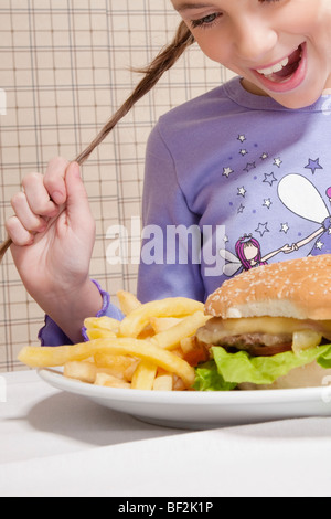 Girl looking at a plate of burger and French fries Stock Photo
