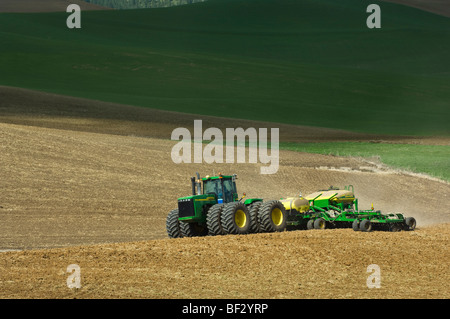 A John Deere tractor and air seeder planting garbanzo beans (chick peas) in the rolling hills of the Palouse / Washington, USA. Stock Photo