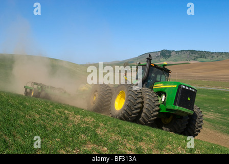 A tractor and air seeder replant areas of winter wheat damaged by lingering snow packs in the rolling hills of the Palouse / USA Stock Photo