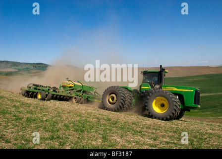 A tractor and air seeder replant areas of winter wheat damaged by lingering snow packs in the rolling hills of the Palouse / USA Stock Photo