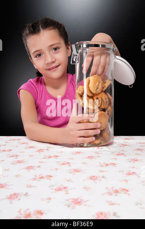 Girl putting her hand into a cookie jar Stock Photo
