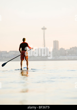 A man paddling on his stand-up paddle board on Elliott Bay with the Seattle Space Needle in the background. Stock Photo