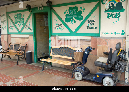 A wheelchair-style mobility scooter is parked near the entrance to a popular Irish Pub in the old towne district of Orange, CA.