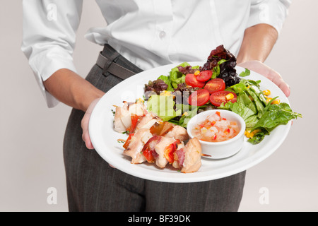 Mid section view of a woman holding a platter of shish kebabs Stock Photo
