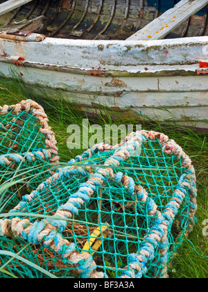 Lobster Pots and a paint-chipped rowing boat on the harbour at Lindisfarne (Holy Island) on the Northumberland coast, England Stock Photo