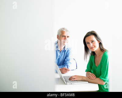 Woman working on computer with colleague Stock Photo