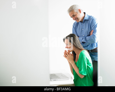 Woman working on computer with colleague Stock Photo