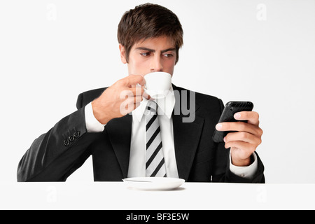 Businessman using a mobile phone and drinking coffee Stock Photo