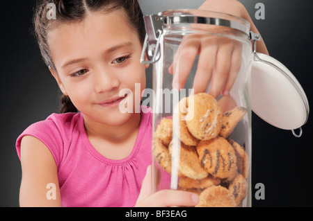 Girl putting her hand into a cookie jar Stock Photo