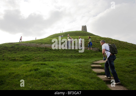 With others in the distance near the hilltop, a group of visitors climb the steps to the summit of the hilltop Glastonbury Tor. Stock Photo