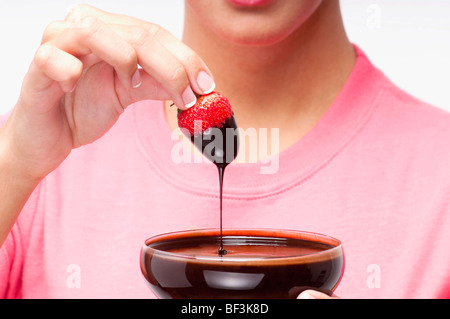 Woman dipping a strawberry in chocolate sauce Stock Photo