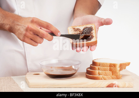 Man applying chocolate sauce on a slice of bread Stock Photo