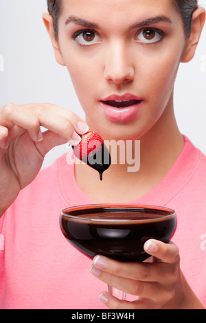Woman dipping a strawberry in chocolate sauce Stock Photo