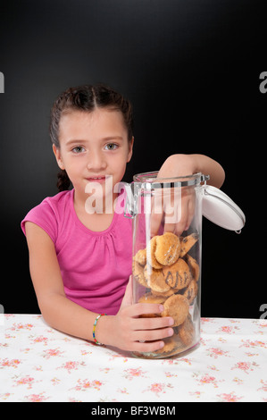 Girl putting her hand into a cookie jar Stock Photo