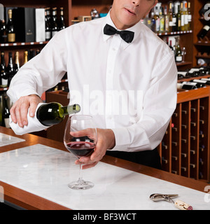 Waiter pouring red wine into a wine glass in a bar Stock Photo