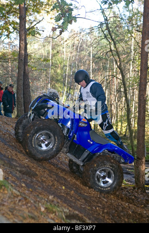 Man rides all-terrain vehicle (ATV) on steep terrain in woods. Trial off-road biking Stock Photo
