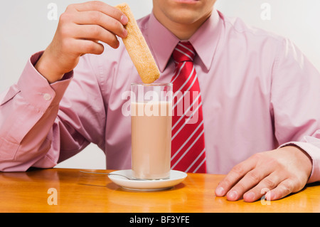Mid section view of a businessman dipping a wafer in milk Stock Photo