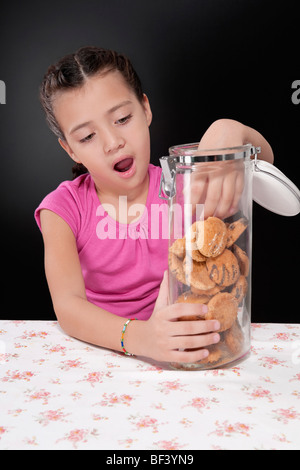 Girl putting her hand into a cookie jar Stock Photo