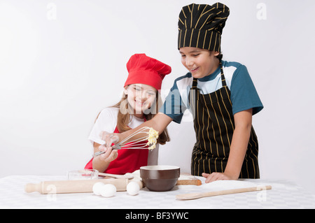 Boy looking at whipped batter with his sister Stock Photo