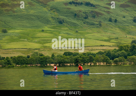 Side view of 2 young caucasian adults paddling a Canadian canoe on a deserted Loch Earn, Perthshire, Scotland. UK. Stock Photo