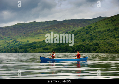 Side view of 2 young caucasian adults paddling a Canadian canoe on a deserted Loch Earn, Perthshire, Scotland. UK Stock Photo