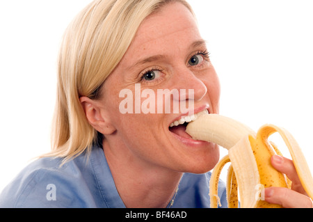 nurse or doctor medical woman eating a healthful ripe banana Stock Photo