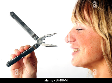Blonde model with Rolson leatherman style copy retractable toolkit including knives pliers and screwdriver Stock Photo