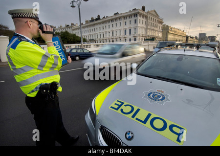 A police officer using a handheld laser camera on a city road to catch speeding motorists Stock Photo