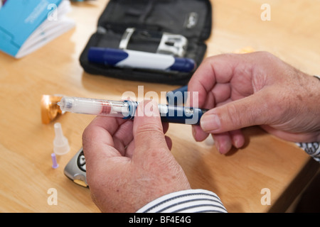 close up of elderly mans hands preparing diabetic injection syringe prior to injecting himself with insulin with novomix flexpen Stock Photo