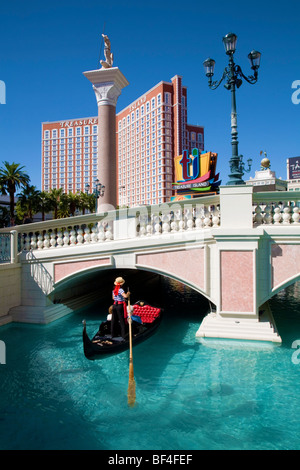 Gondolier on the Venetian Hotel canal with Treasure Island (TI) Hotel in the background, Las Vegas Stock Photo