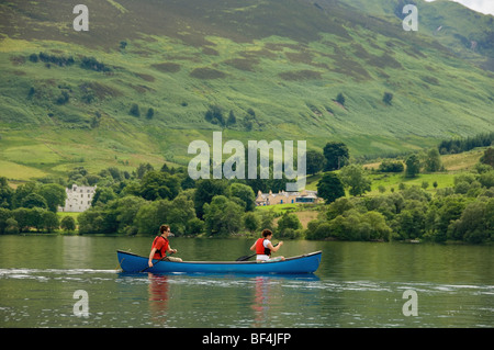 Side view of 2 young caucasian adults paddling a Canadian canoe on a deserted Loch Earn, Perthshire, Scotland. UK. Stock Photo