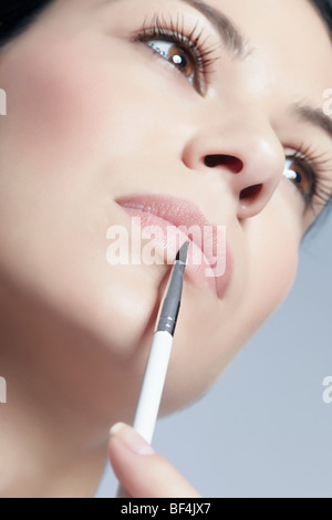 Young woman applying lip gloss with a brush, beauty Stock Photo