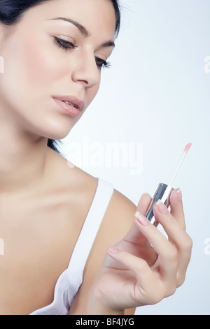 Young woman looking at her lip gloss in her hand, beauty Stock Photo