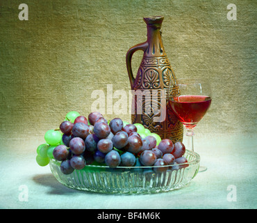 Still-life from grapes, bottle and glass of wine on canvas background Stock Photo