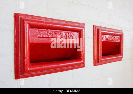Red letterbox and Newspaper box in old style inset into brick wall Stock Photo