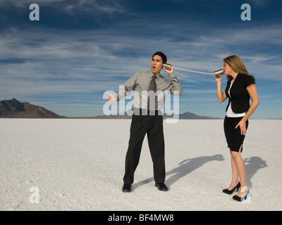 Hispanic businesspeople talking on can and string telephone Stock Photo ...