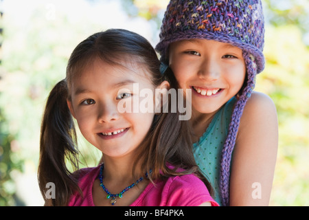 Portrait of two smiling girls hugging in garden Stock Photo - Alamy
