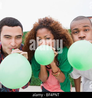 Friends blowing up green balloons Stock Photo