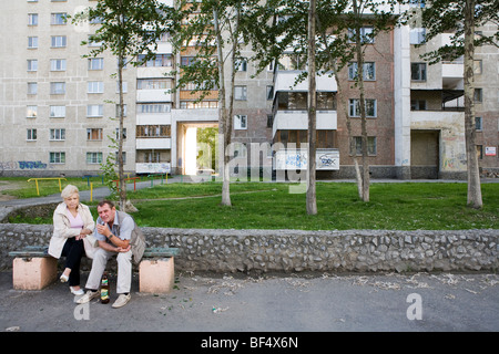 Couple sitting outside apartment blocks, Ekaterinburg, Urals, Russia Stock Photo