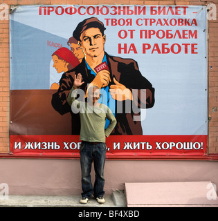 Man standing in front of traditional soviet propaganda poster, portrait, Ekaterinburg, Urals, Russia Stock Photo