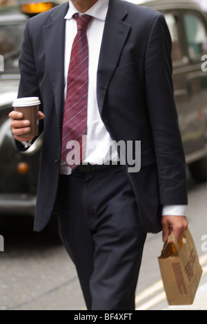 Fast food lunchtime takeaway snack in a bag. City of London office worker taking his lunch back to the office carrying a cup of coffee. 2009 2000s Stock Photo